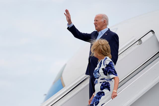 Joe Biden and Jill Biden wave as they descend aeroplane steps