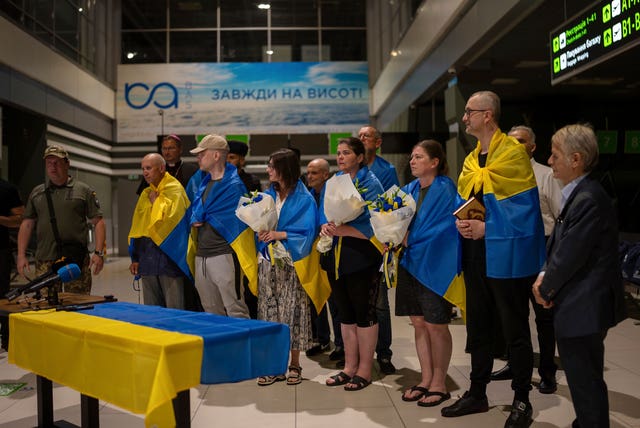 Some of the prisoners who were released, with flags around their shoulders, at Kyiv Airport, Ukraine
