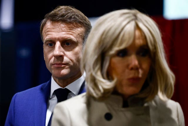 French President Emmanuel Macron and his wife Brigitte Macron stand in the voting station before voting in Le Touquet-Paris-Plage, northern France