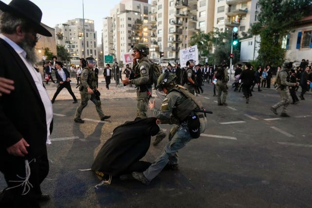 An Israeli police officer drags an ultra-Orthodox man in the street