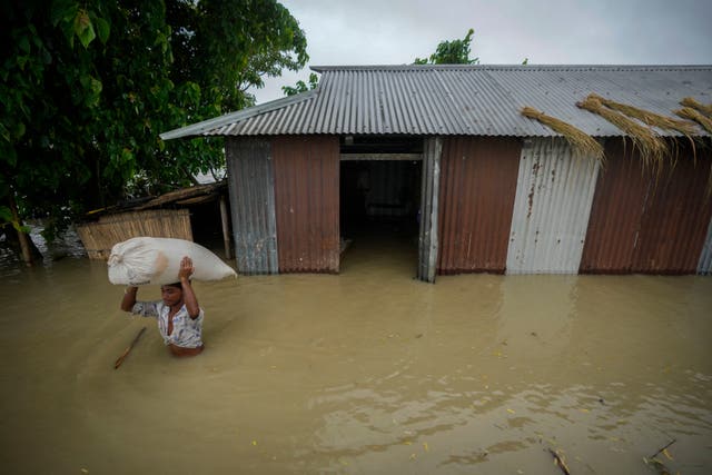 A flood victim carries a sack of rice from his submerged house in Sildubi village in Morigaon district in the northeastern state of Assam, India 