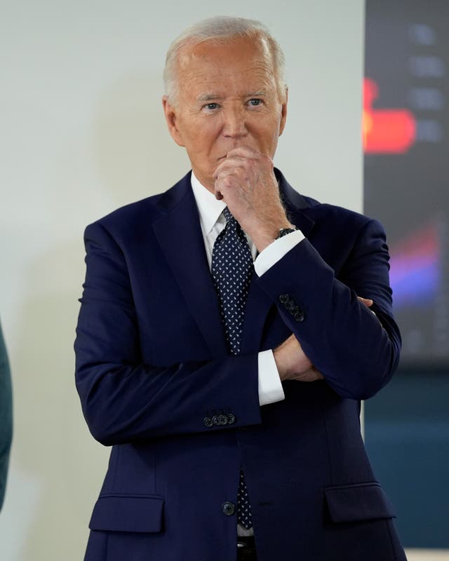 Joe Biden in a suit, his hand is to his mouth