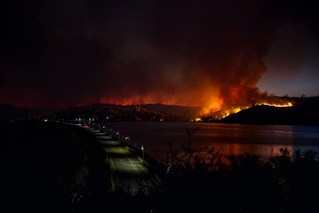 A wide shot showing an empty road and a large fire in the distance