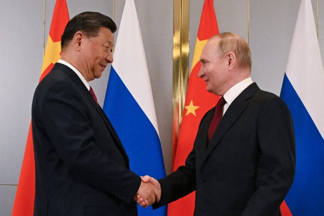Russian President Vladimir Putin, right, and Chinese President Xi Jinping shake hands