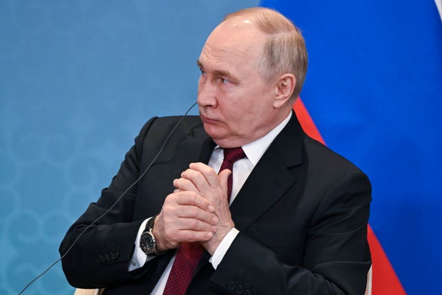 Putin sitting in a chair with his hands together