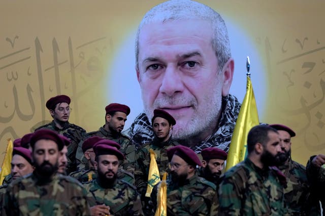 Hezbollah fighters stand next to a poster of their comrade, senior commander Mohammad Naameh Nasser