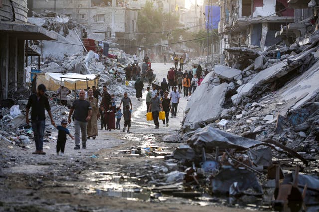 Palestinians displaced by the Israeli air and ground offensive on the Gaza Strip, walk through a dark streak of sewage flowing into the streets of Khan Younis