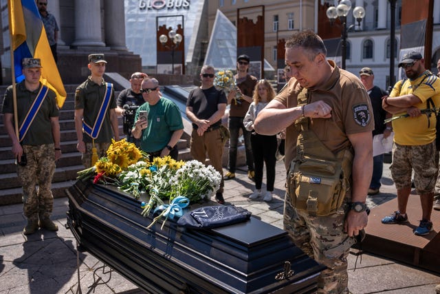 A soldier salutes as he stands over a coffin