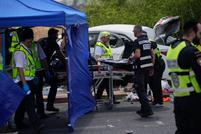 Police and people in high-vis jackets stand by a blue tent