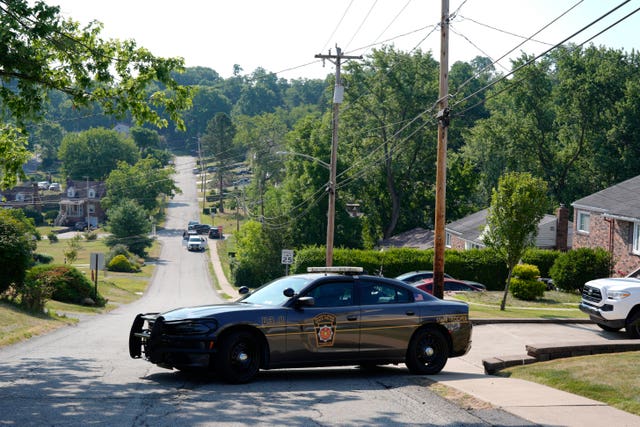 A car is parked across a road with forest in the background