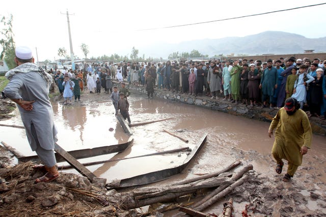 People gather to clear the rubble from a house that was partially destroyed by a landslide.