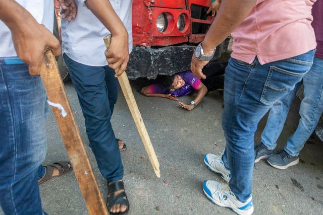 A student hides underneath a vehicle as students clash at Jahangir Nagar University