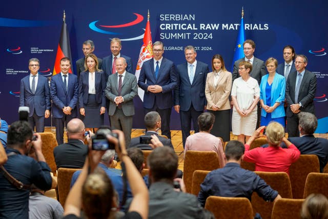 Serbian President Aleksandar Vucic, centre, poses with German Chancellor Olaf Scholz, centre left, and European Commission Vice President Maros Sefcovic, centre right, among a group of people at the Serbia Palace in Belgrade on stage with flags behind