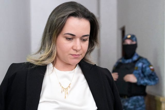 Lawyer Maria Korchagina looking down in a court building in Yekaterinburg, Russia, with an armed masked guard in the background 