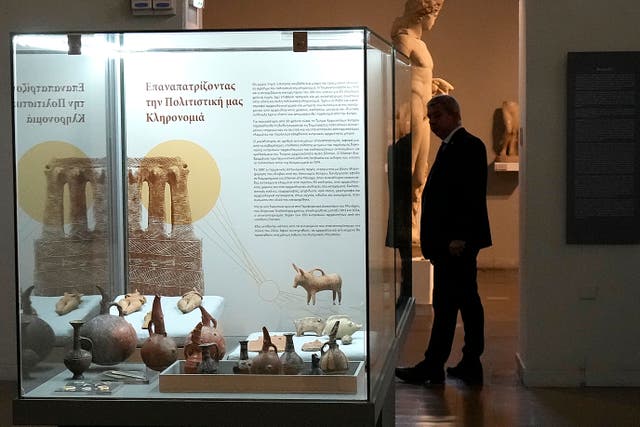 A security officer stands behind antiquities displayed in a glass case