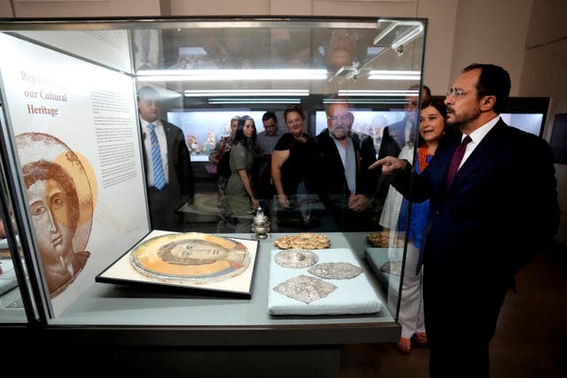 President Nikos Christodoulides stands in front of an Orthodox Christian icon in a glass case