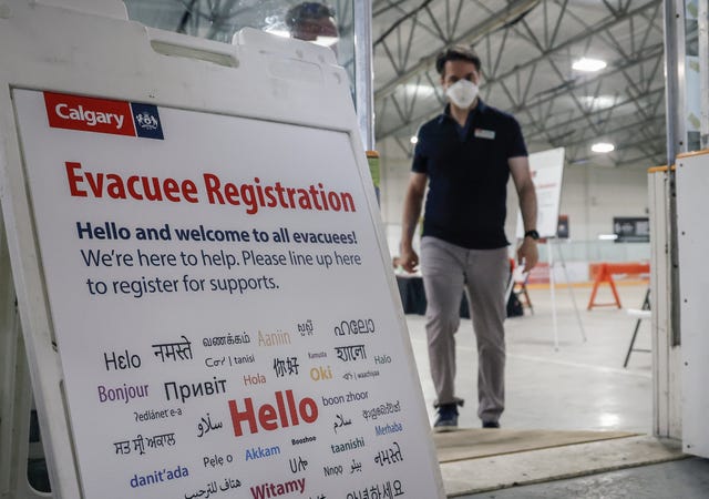 A man in a mask approaches an Evacuee Registration sign