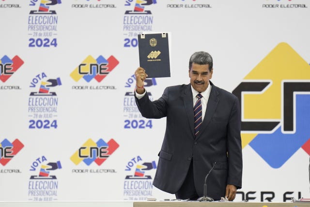 Venezuelan President Nicolas Maduro holds up his certification from the National Electoral Council (CNE) that declares him the winner of the presidential election, at the CNE in Caracas, Venezuela 