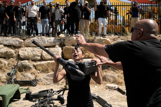 A woman from the Druze minority is overcome by emotion as she holds a motorized scooter at the site where 12 children and teens were killed in a rocket strike on a soccer field