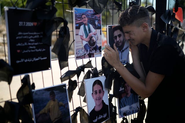 A youth from the Druze minority weeps over a makeshift memorial for 12 children and teens killed in a rocket strike on a soccer field in the Israeli-annexed Golan Heights 