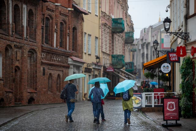 People shelter from the rain under umbrellas in Vilnius, Lithuania 