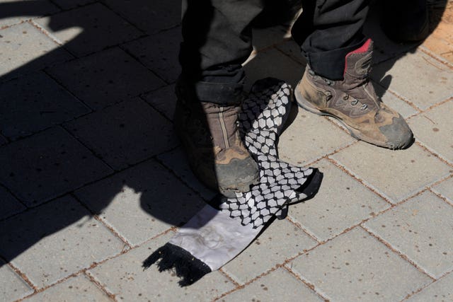 Right-wing Israelis, one stomping on a Palestinian scarf, protest outside of the hearing