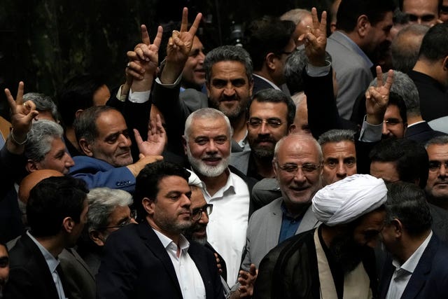 Mr Haniyeh flashes a victory sign as he is surrounded by a group of Iranian legislators