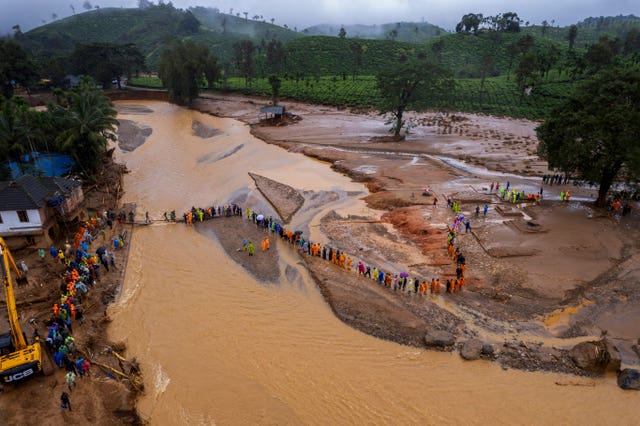 Rescuers on their second day of mission following Tuesday’s landslides cross a river at Chooralmala, Wayanad district, Kerala state