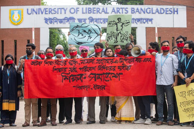 University teachers wear red masks and hold a banner as they demand justice for the victims killed in the recent countrywide deadly clashes during a protest in Dhaka, Bangladesh