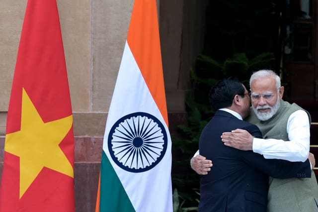 Narendra Modi, right, hugs his Vietnamese counterpart Pham Minh Chinh next to Indian and Vietnamese flags