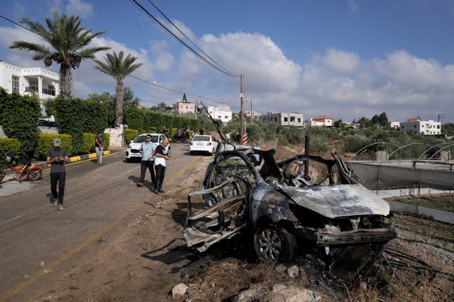 People gather around a destroyed car