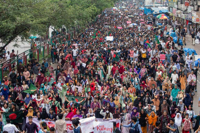 Thousands of protests, with placards and flags, march down a road