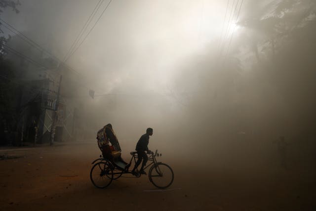 A rickshaw puller rides in the smoke caused by a burning shopping centre in Dhaka 