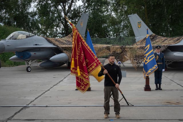 A man with a flag and two fighter jets behind