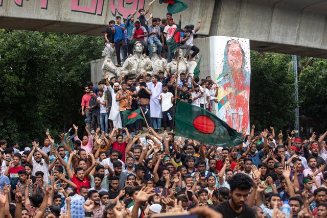 Protesters climb a public monument as they celebrate the news of Prime Minister Sheikh Hasina’s resignation, in Dhaka