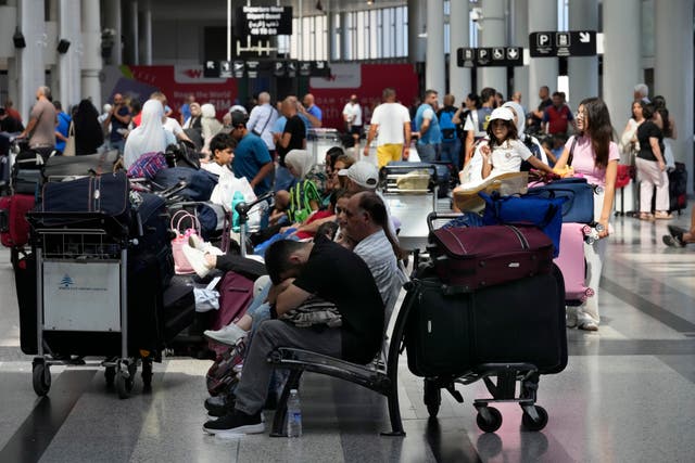 People with bags wait at an airport