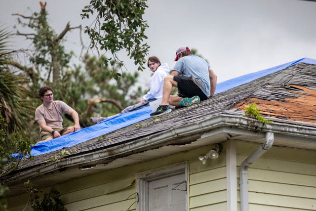 Residents repair their roof as high winds from an outer band from Tropical Storm Debby passed over the Isle of Palms in South Carolina