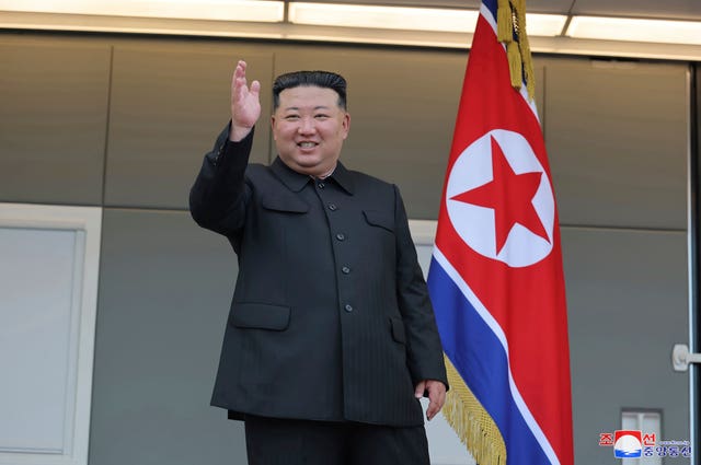 Kim Jong Un waves before a North Korean flag