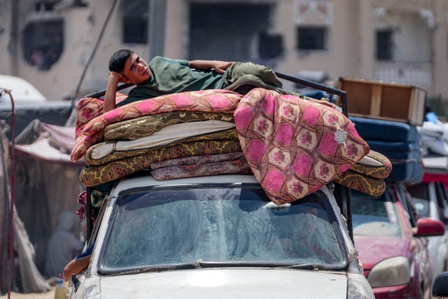 A man lies on mattresses on top of a car