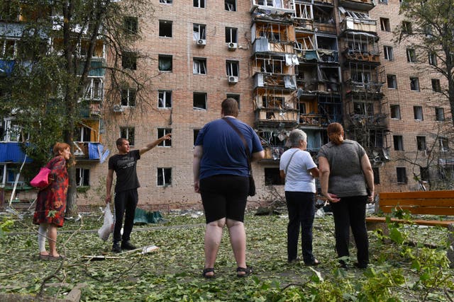 Residents of an apartment building damaged after Ukrainian shelling stand near the building in Kursk, Russia