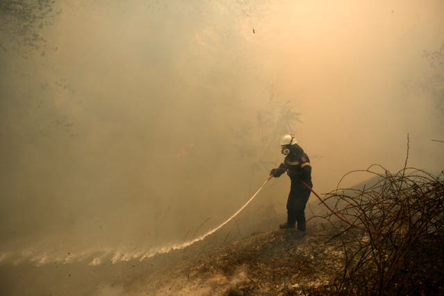 A firefighter tries to extinguish a fire in northern Athens