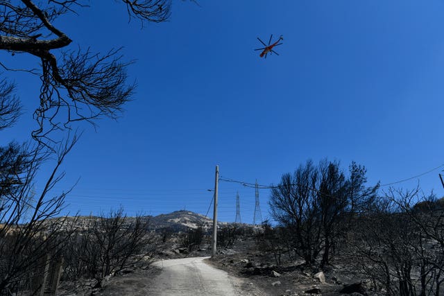 A firefighting helicopter flies in the Nea Penteli suburb of Athens