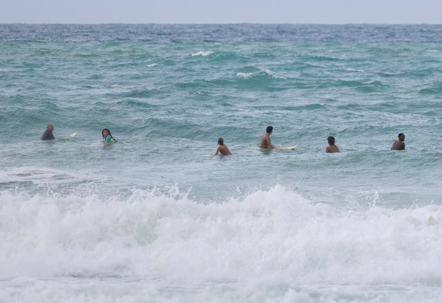 Surfers wait for a wave before the passage of Tropical Storm Ernesto at La Pared beach in Luquillo, Puerto Rico