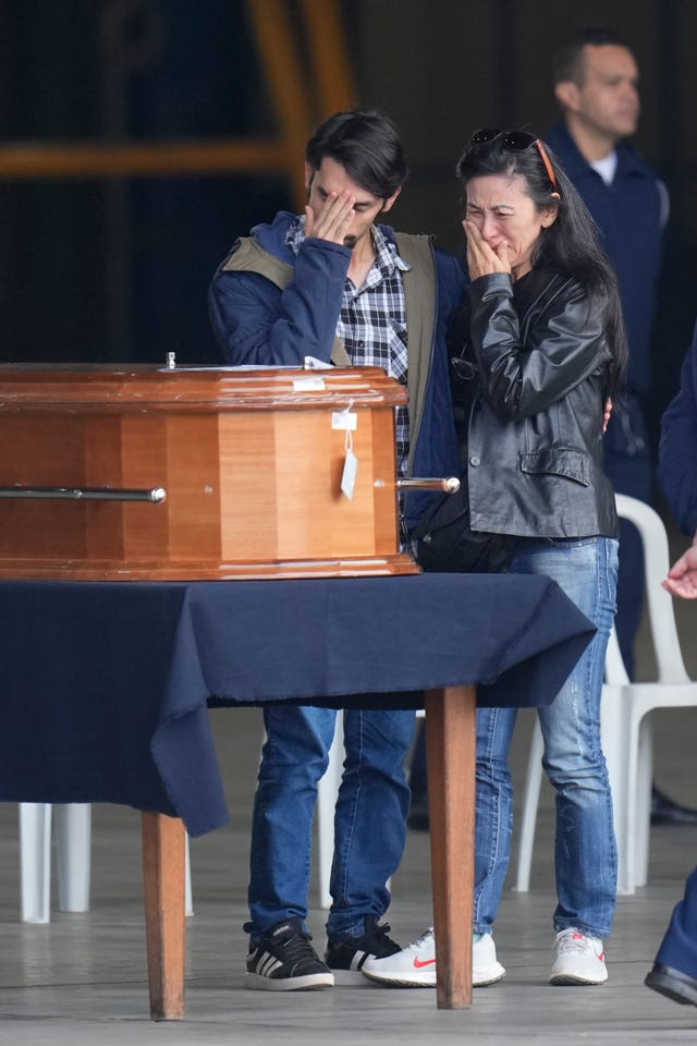 Family members of a plane crash victim stand by their remains during a religious ceremony shortly before many of the victim’s remains are placed in an Air Force plane