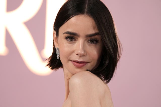Lily Collins looks into camera with silver jewel earrings 