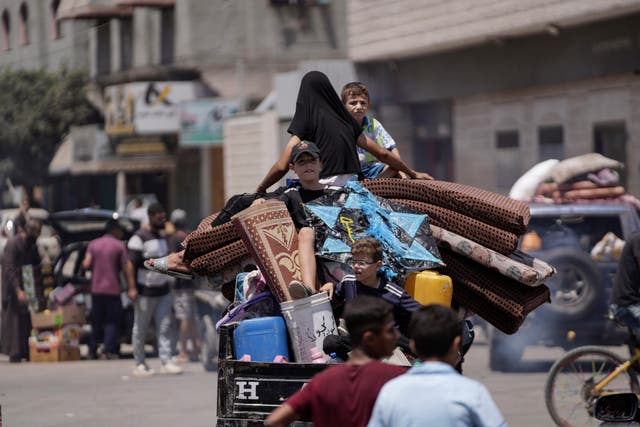 Children sit on a pile of carpets and household belongings