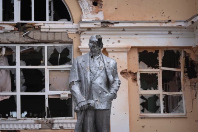 Damaged Lenin statue in front of a damaged building