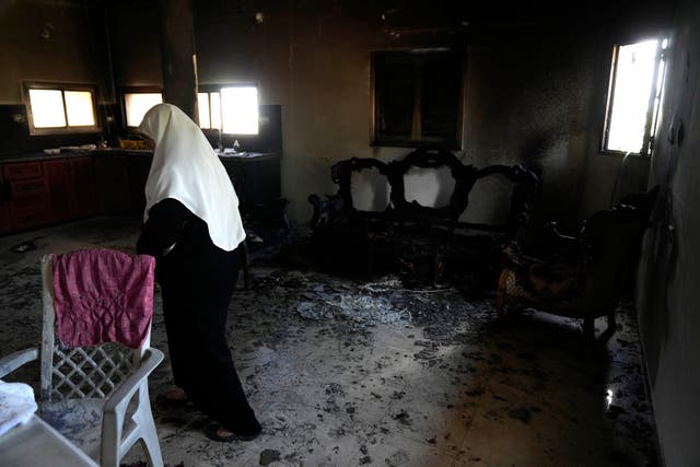 A Palestinian woman stands in her home the morning after it was torched in a rampage by Israeli settlers in the West Bank village of Jit