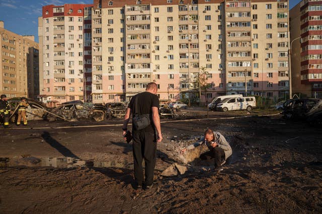 Young men look at shrapnel after a Russian air strike on a residential neighbourhood in Sumy, Ukraine