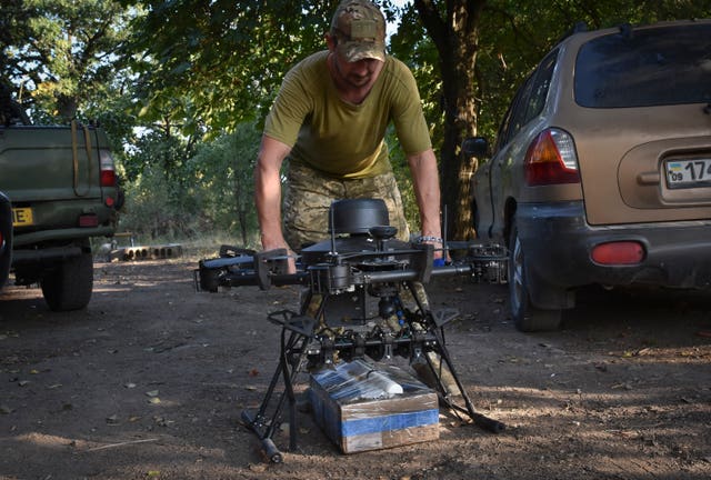 A soldier of Ukraine’s 141st separate infantry brigade loads a drone with a parcel for soldiers on a mission at the frontline in Zaporizhzhia region, Ukraine